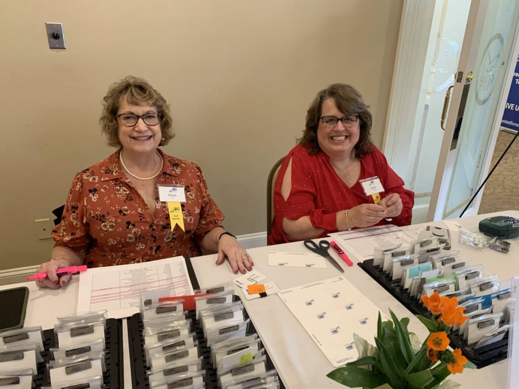 Two women sit behind registration desk.