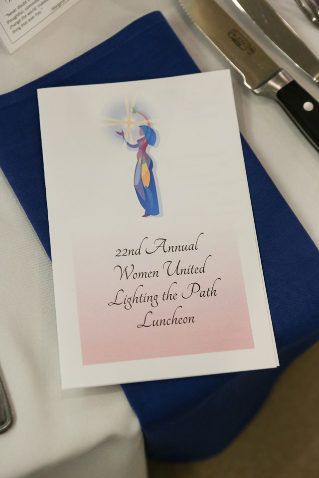 Program for 22nd Annual Women United Lighting the Path Luncheon rests on top of napkin