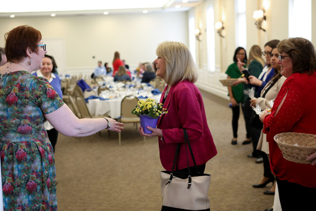 Smiling woman accepts flowers from another woman.