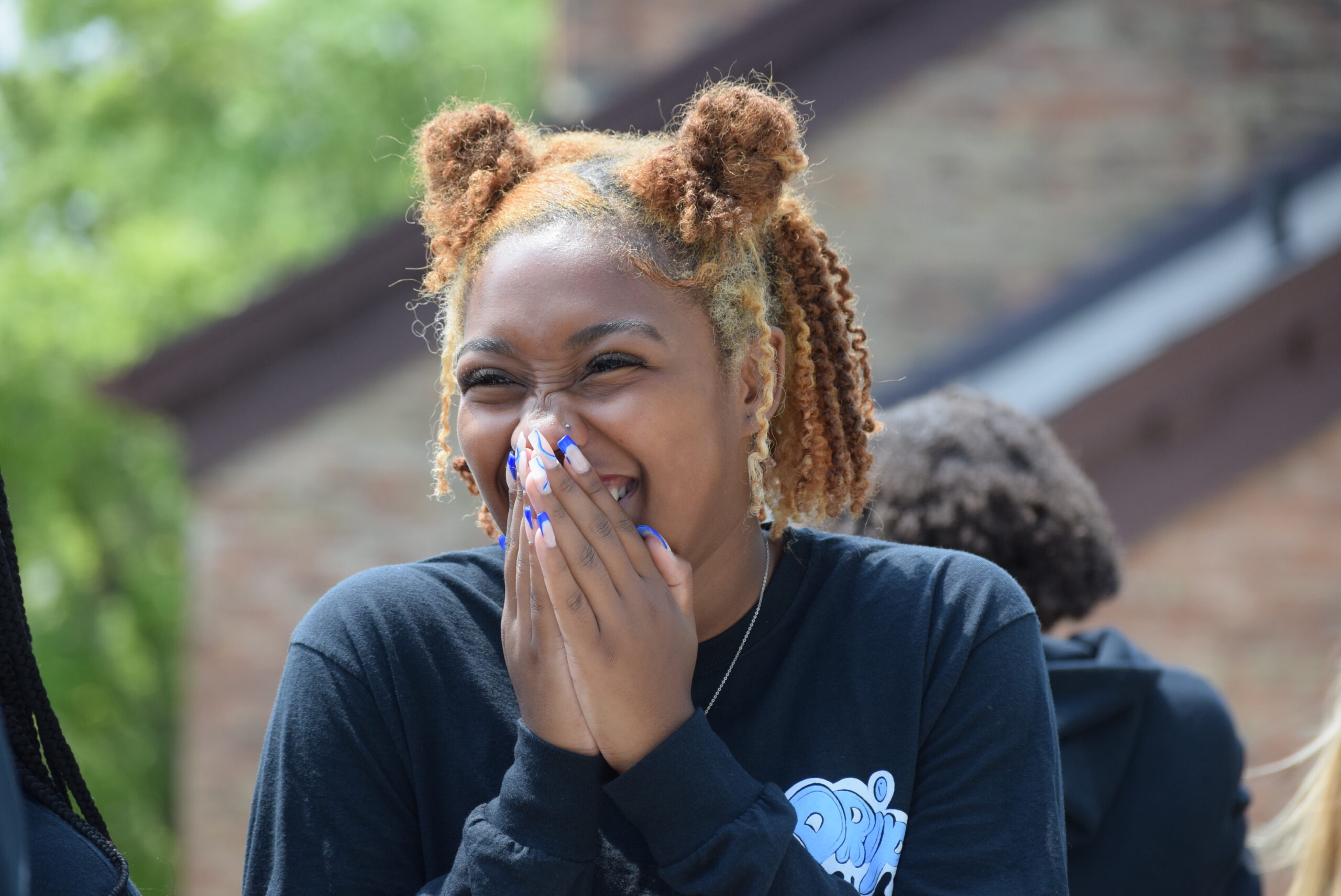 Girl smiles with hands over her mouth.