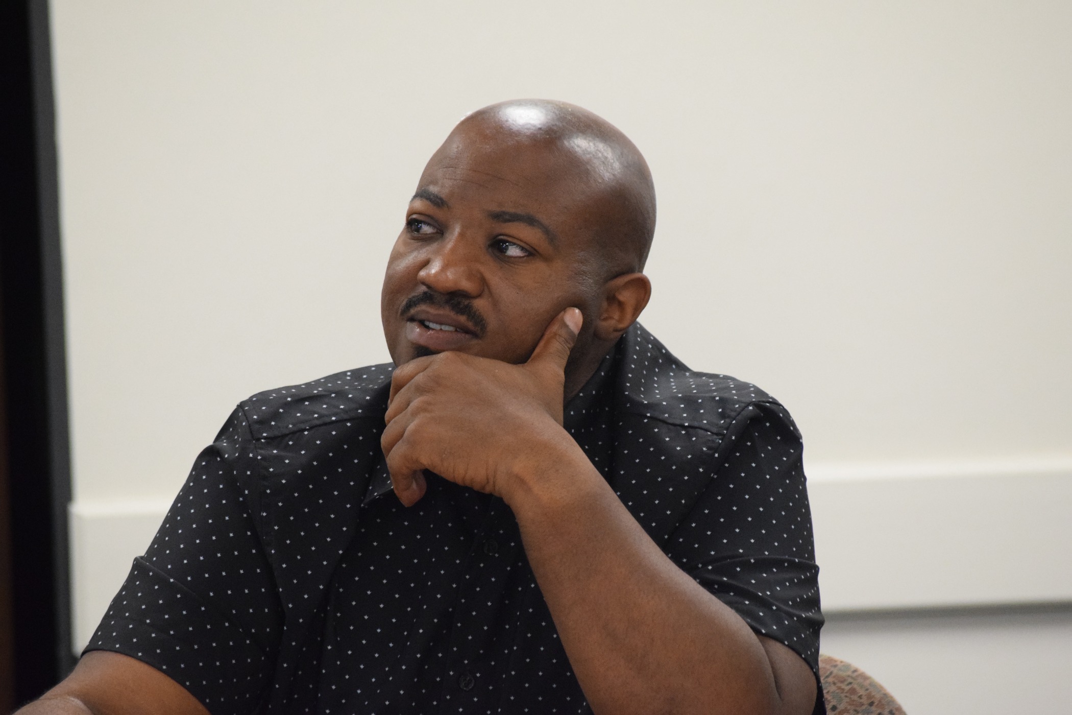 A man rests his chin in his hand as he sits at a table.