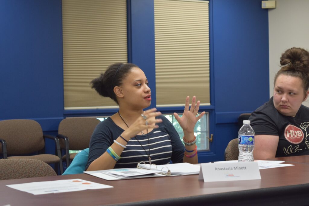 A woman sits at a table, talking.