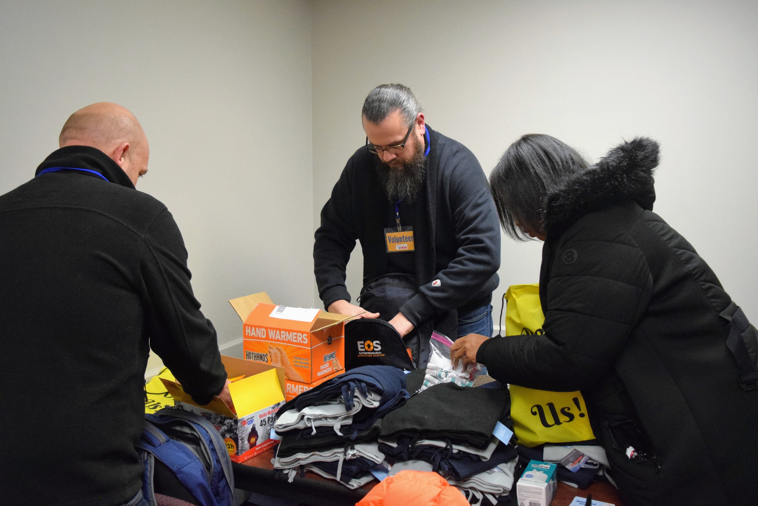 Three people pack bags of hand warmers.