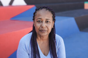 Senior african woman looking on camera - Elderly person in the city with colorful background