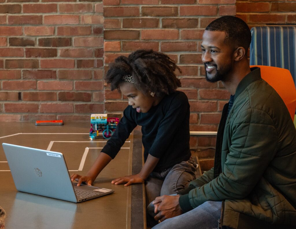 A man and girl work together at a computer.