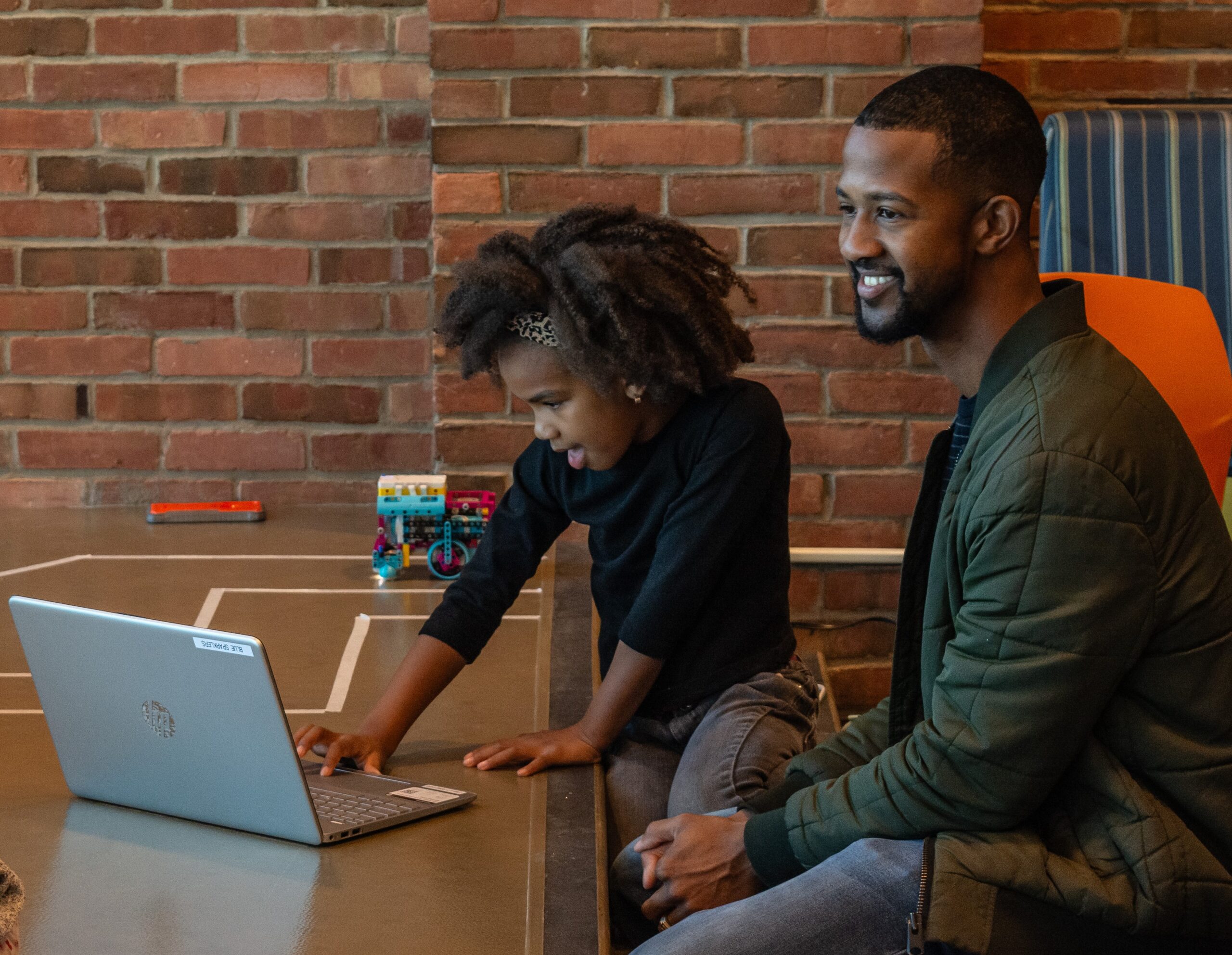 A man and girl work together at a computer.