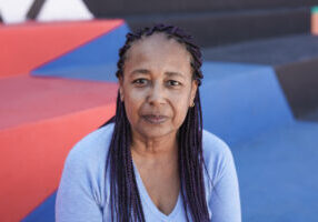 Senior african woman looking on camera - Elderly person in the city with colorful background